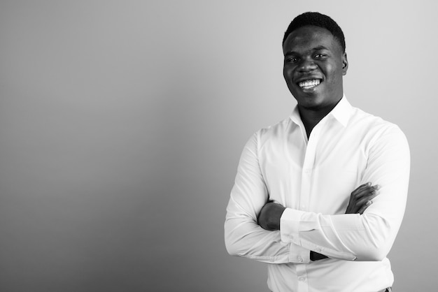 joven empresario africano con camisa blanca contra la pared blanca. en blanco y negro
