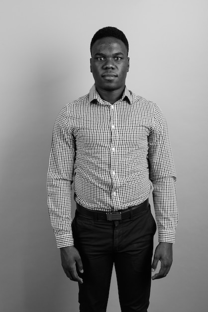 joven empresario africano con pelo afro contra la pared blanca. en blanco y negro