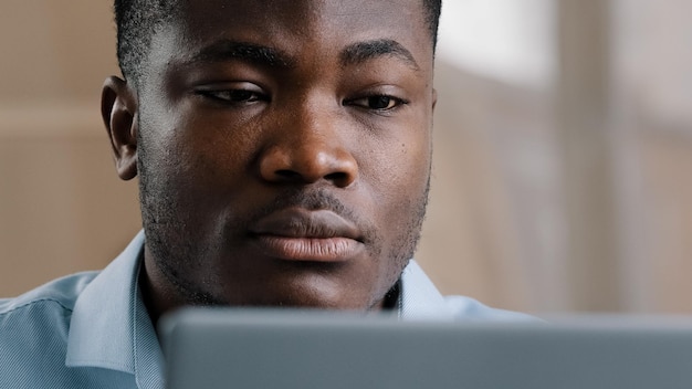 Un joven empresario africano serio usando una computadora portátil crea un diseño web para información de investigación de startups