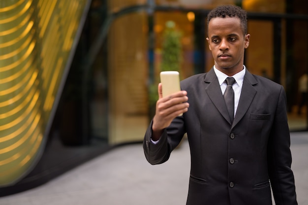 Joven empresario africano mediante teléfono móvil al aire libre