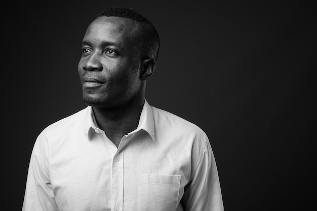 joven empresario africano vistiendo camisa contra la pared gris. en blanco y negro