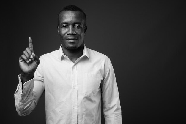 joven empresario africano vistiendo camisa contra la pared gris. en blanco y negro