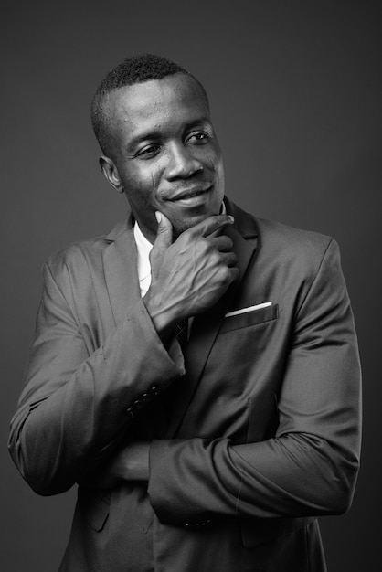 joven empresario africano vistiendo traje contra la pared gris. en blanco y negro