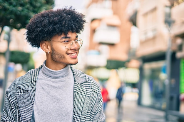 Joven empresario afroamericano sonriendo feliz de pie en la ciudad