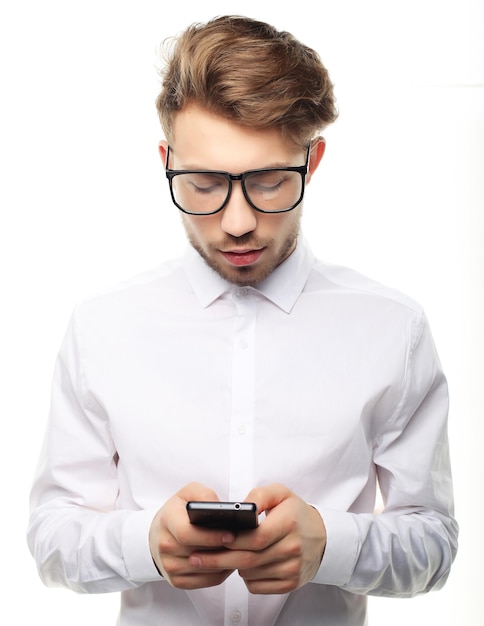 Joven empresario alegre escribiendo sms en su teléfono móvil