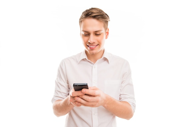 Joven empresario alegre escribiendo sms en su teléfono móvil