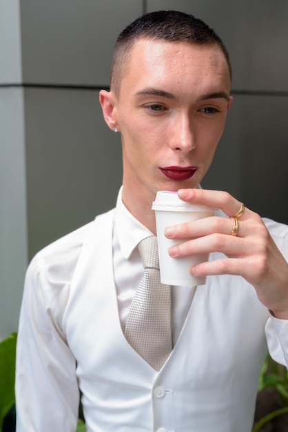 Joven empresario andrógino tomando café