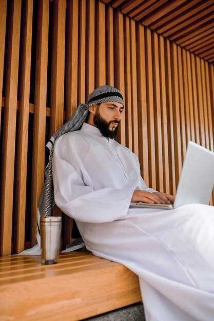 Joven empresario árabe trabajando en una computadora portátil y mirando involucrado