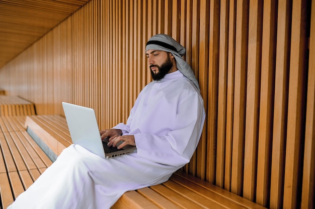 Joven empresario árabe trabajando en una computadora portátil y mirando involucrado
