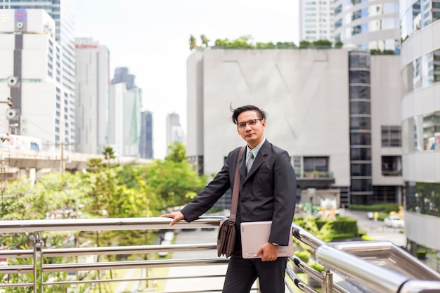 Joven empresario de Asia en traje con su computadora portátil al aire libre