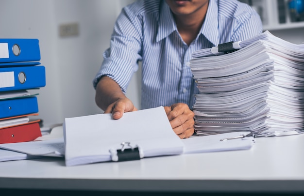 Foto joven empresario asiático agotado con escritorio desordenado y pila de papeles, trabajo ocupado, exceso de trabajo.