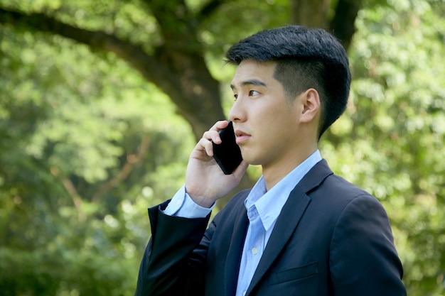 Joven empresario asiático caminando en el parque