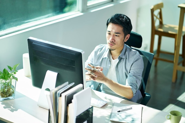 Foto joven empresario asiático contemplando en la oficina