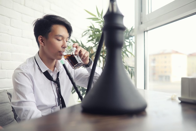 Un joven empresario asiático espera pareja en un café. Reunión de negocios en el restaurante. Un joven coreano hablando por teléfono en una cafetería.