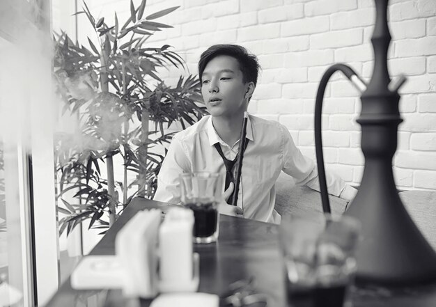 Un joven empresario asiático está esperando a un socio en un café Reunión de negocios en el restaurante Un joven coreano hablando por teléfono en un café