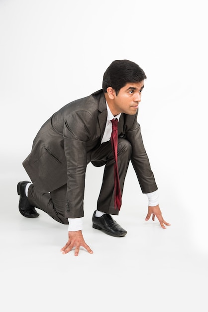 Joven empresario asiático inteligente y decidido indio corriendo o de pie en la posición inicial, aislado en blanco