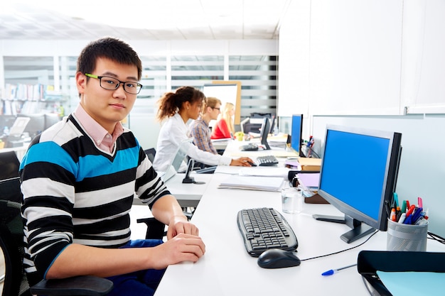 Joven empresario asiático en oficina con computadora