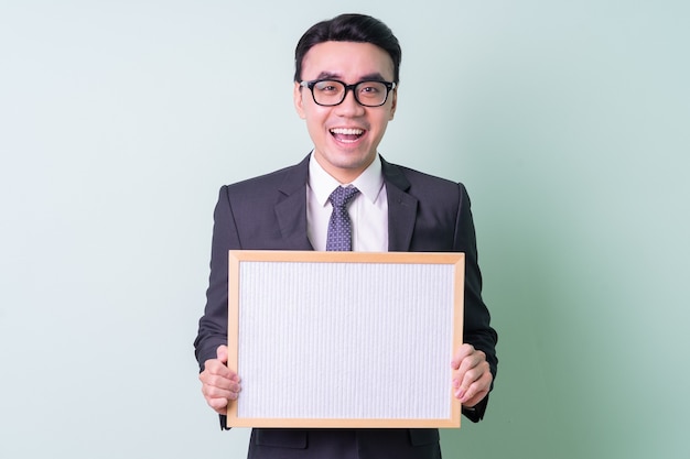 Joven empresario asiático posando sobre fondo verde