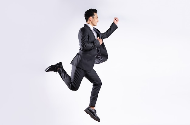 Joven empresario asiático saltando sobre blanco