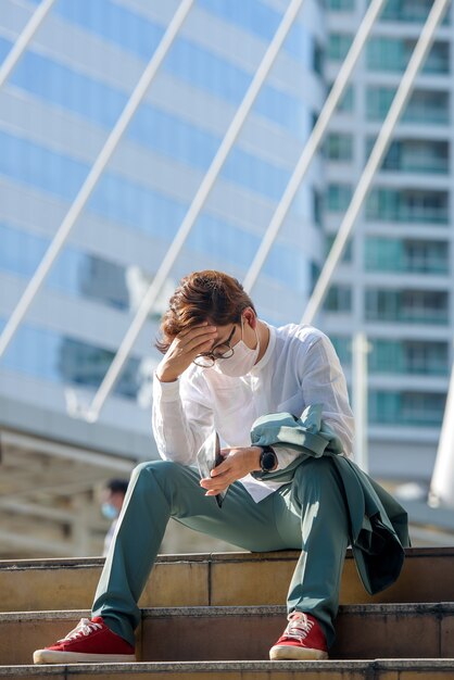 Joven empresario asiático sentado triste Desempleo en crisis COVID-19 Una billetera vacía en manos de un joven asiático.