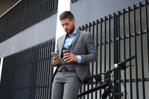 Joven empresario con bicicleta y smartphone en las calles de la ciudad.