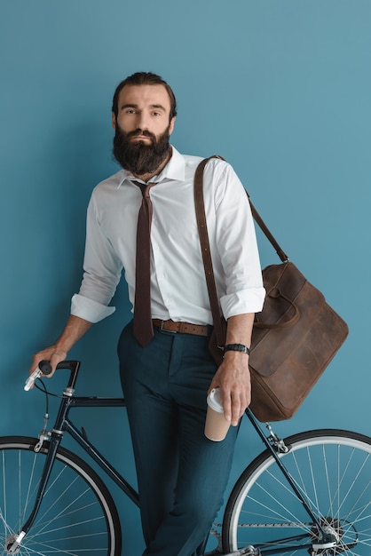 Joven empresario con bicicleta vintage y café para llevar