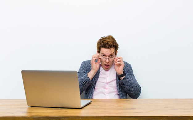 Joven empresario cabeza roja trabajando en su escritorio con una computadora portátil