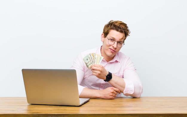 Joven empresario cabeza roja trabajando en su escritorio, concepto de dinero