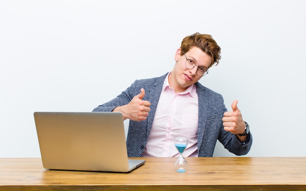 Joven empresario cabeza roja trabajando en su escritorio con un reloj. concepto de tiempo