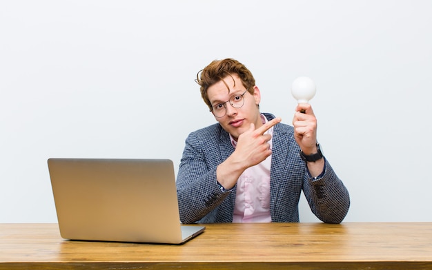 Joven empresario cabeza roja trabajando en su escritorio teniendo una idea