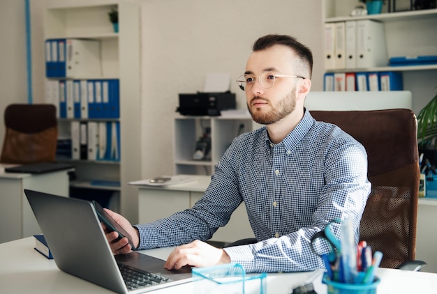 Joven Empresario con camisa trabajando en su laptop en una oficina