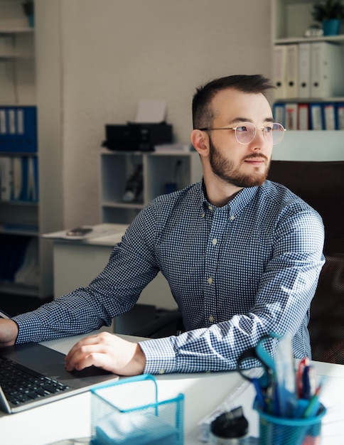 Joven Empresario con camisa trabajando en su laptop en una oficina