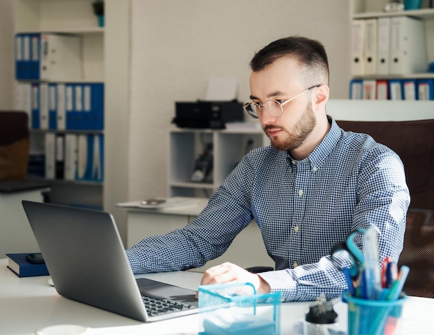 Joven Empresario con camisa trabajando en su laptop en una oficina