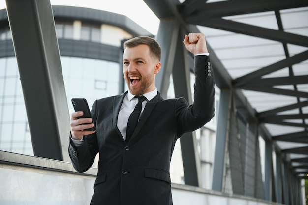 Joven empresario confiado usando teléfono celular en la ciudad