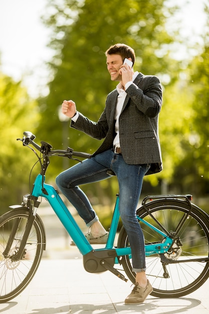 Joven empresario en la ebike mediante teléfono móvil