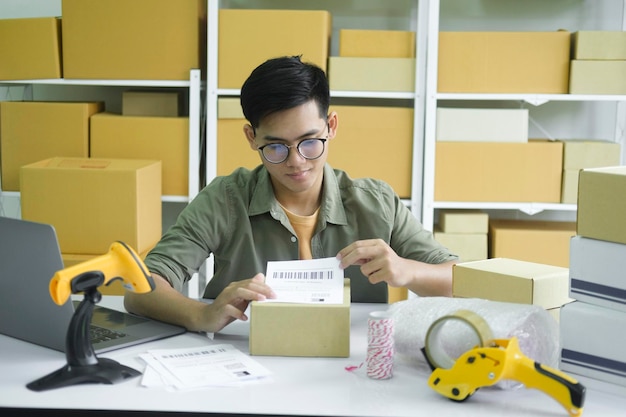 Joven empresario empacando productos de pedidos en línea para envío