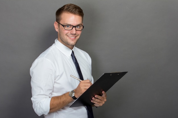 Joven empresario escribiendo en un portapapeles