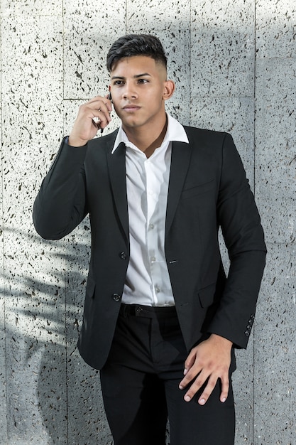 Foto joven empresario étnico hablando por teléfono inteligente