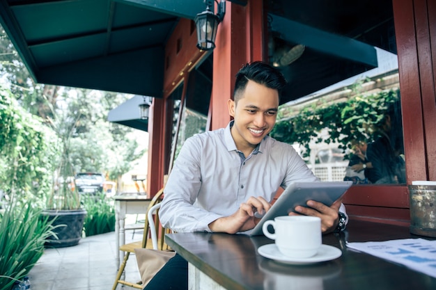 Joven empresario exitoso con tableta en café