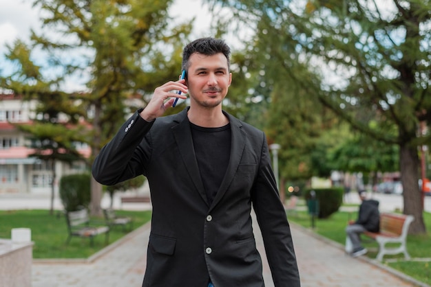 Joven empresario feliz hablando por su teléfono al aire libre