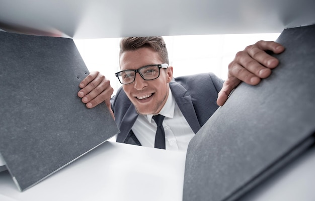 Foto joven empresario con gafas está sonriendo y mirando a la cámara tiene carpetas para documentos