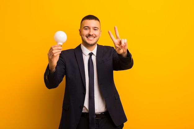 Joven empresario guapo contra el fondo plano con una bombilla