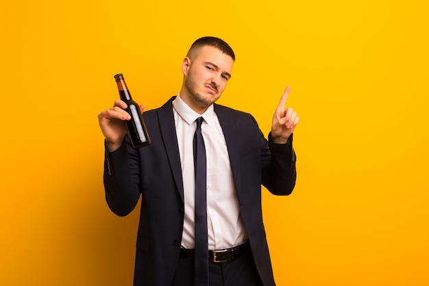 Joven empresario guapo contra el fondo plano con una cerveza