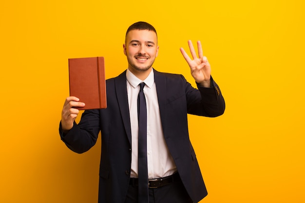 Joven empresario guapo contra el fondo plano con un libro diario