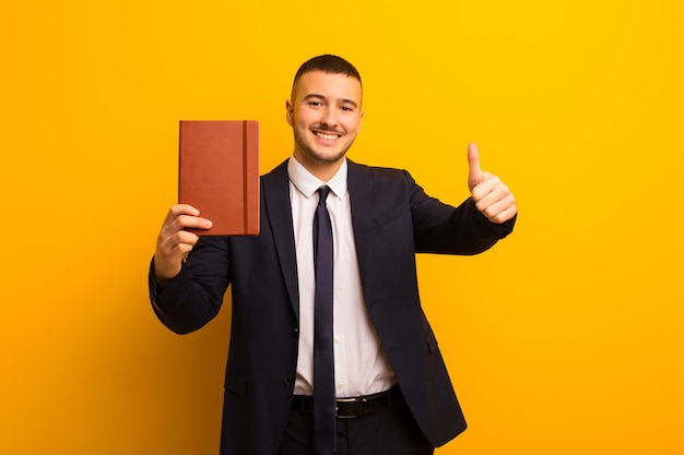 Joven empresario guapo contra la pared plana con un libro diario