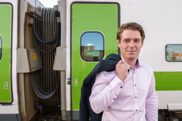 Foto joven empresario guapo delante del tren en la estación de tren