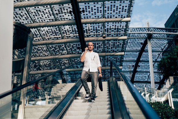 Joven empresario guapo en una escalera mecánica