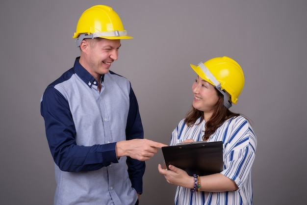 joven empresario guapo y maduro empresaria asiática vistiendo hardhat