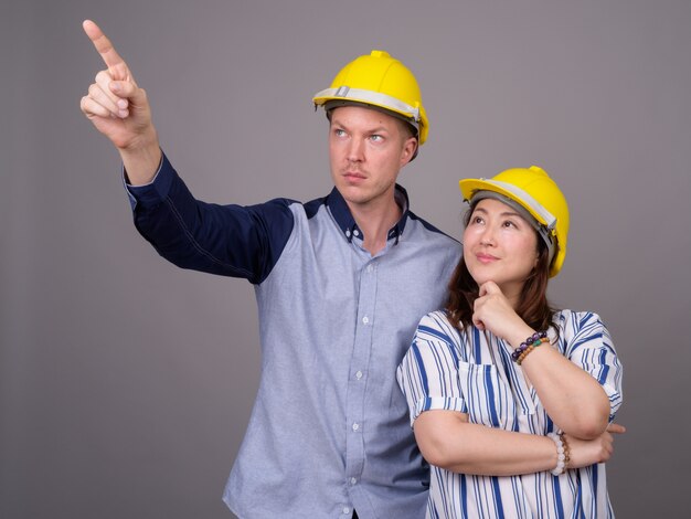 joven empresario guapo y maduro empresaria asiática vistiendo hardhat