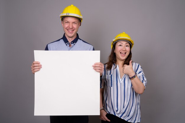 Foto joven empresario guapo y maduro empresaria asiática vistiendo hardhat